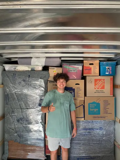 A mover next to wrapped furniture and stacked boxes