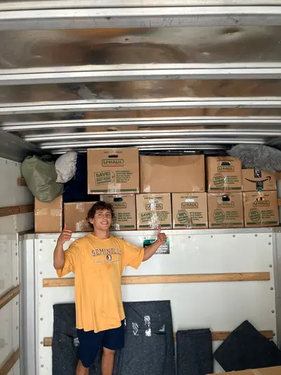 A mover in front of moving boxes loaded in a truck