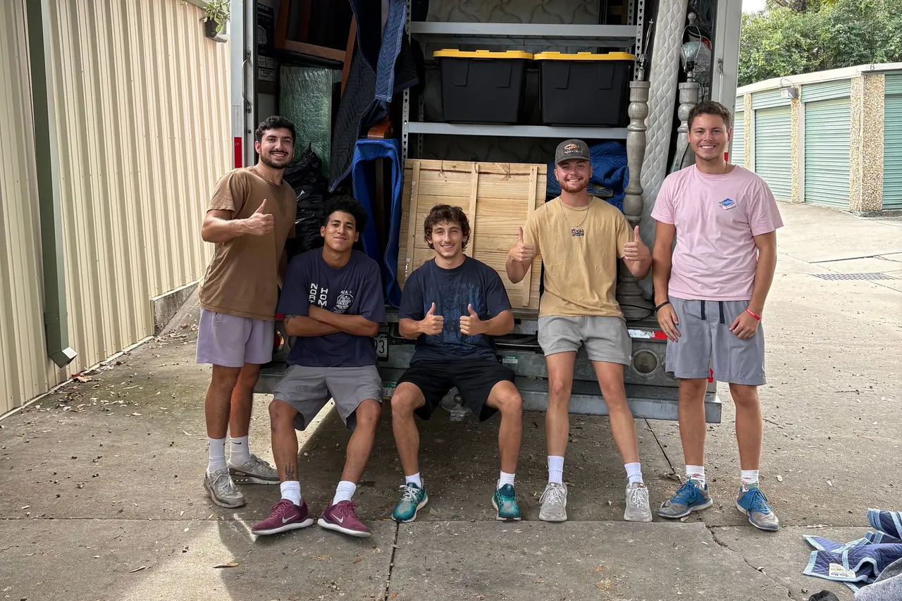 Five Express Movers crew members giving a thumbs up on the tailgate of a loaded moving truck