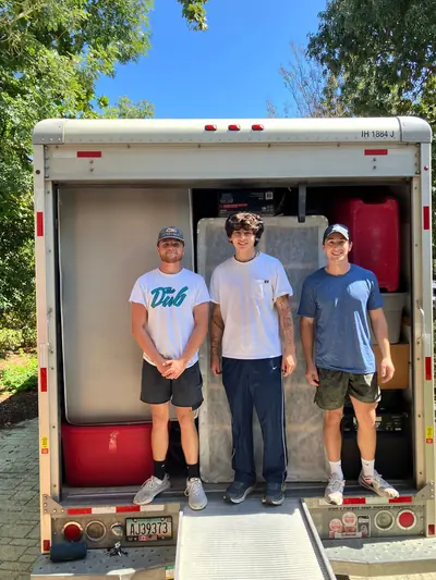 Three crew members in front of an open moving truck