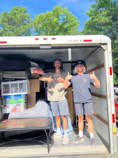 Two crew members giving a thumbs up in a loaded moving truck