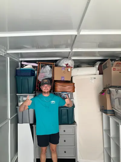 A mover giving a thumbs up in front of a dresser and bins loaded in a truck
