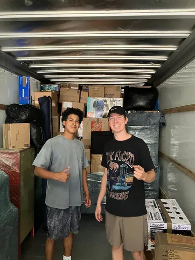 Two movers standing in front of a packed load in a moving truck