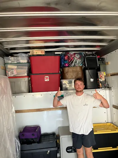 A mover giving two thumbs up in front of neatly stacked totes